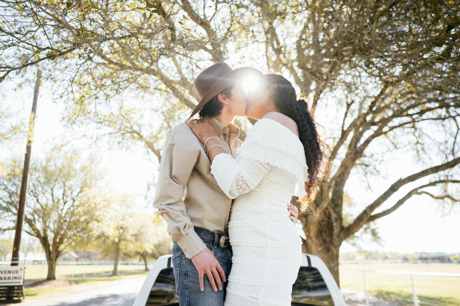 Couple kissing beneath oak trees at golden hour during a Texas country engagement session