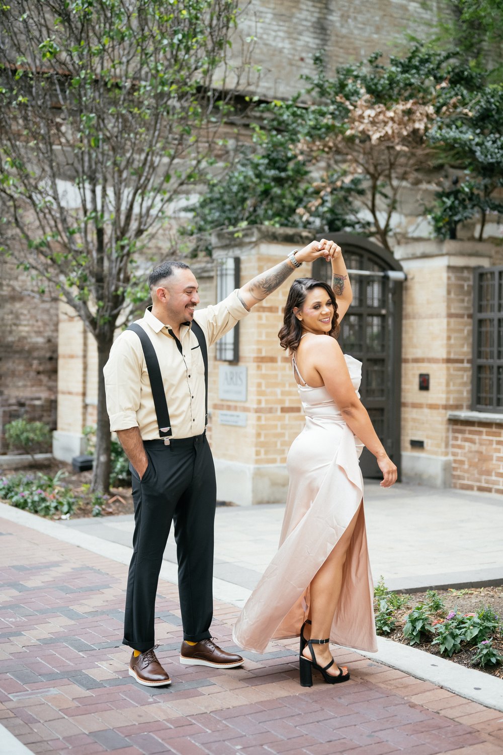 Groom twirling his bride in a historic brick courtyard in Houston